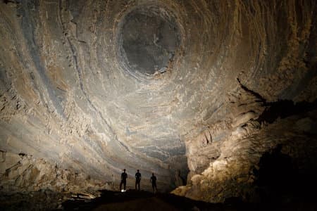Climber ascends a steep limestone wall with ropes inside Son Doong Cave