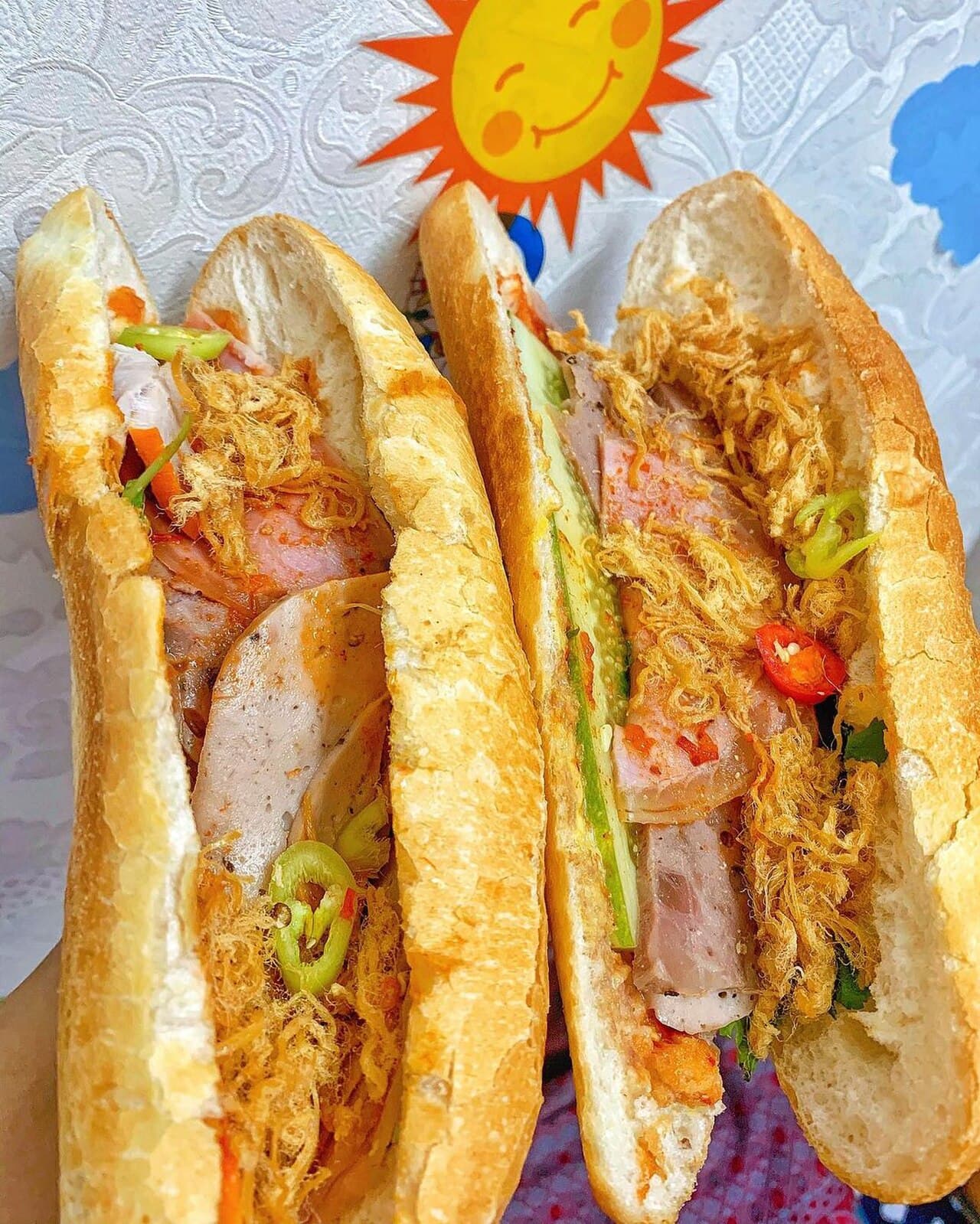 An assortment of bánh mì sandwiches with various fillings displayed at a Vietnamese eatery.